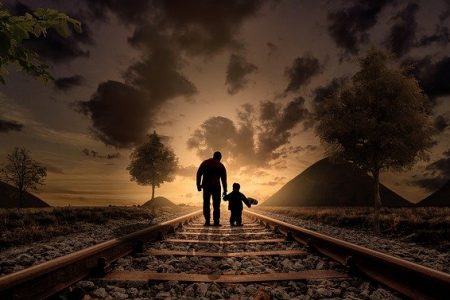 father and son walking on train track