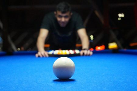 blue pool table with ball and person setting game up